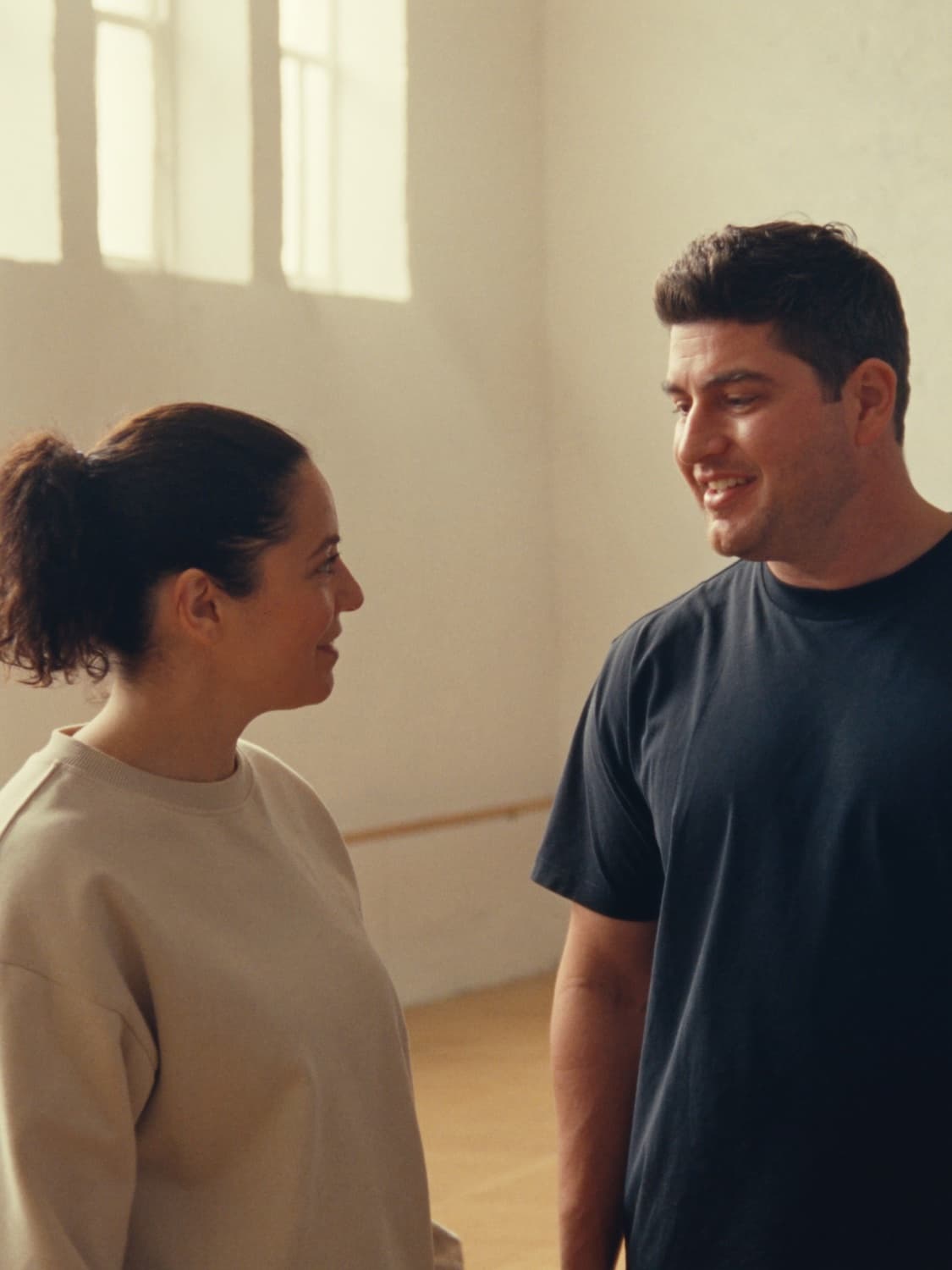 A coach and her client talking and smiling in a sunlit studio